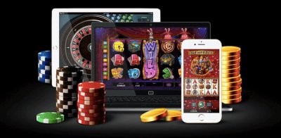 Platta, laptop och mobil med casinospel samt högar med spelmarker och guldmynt
